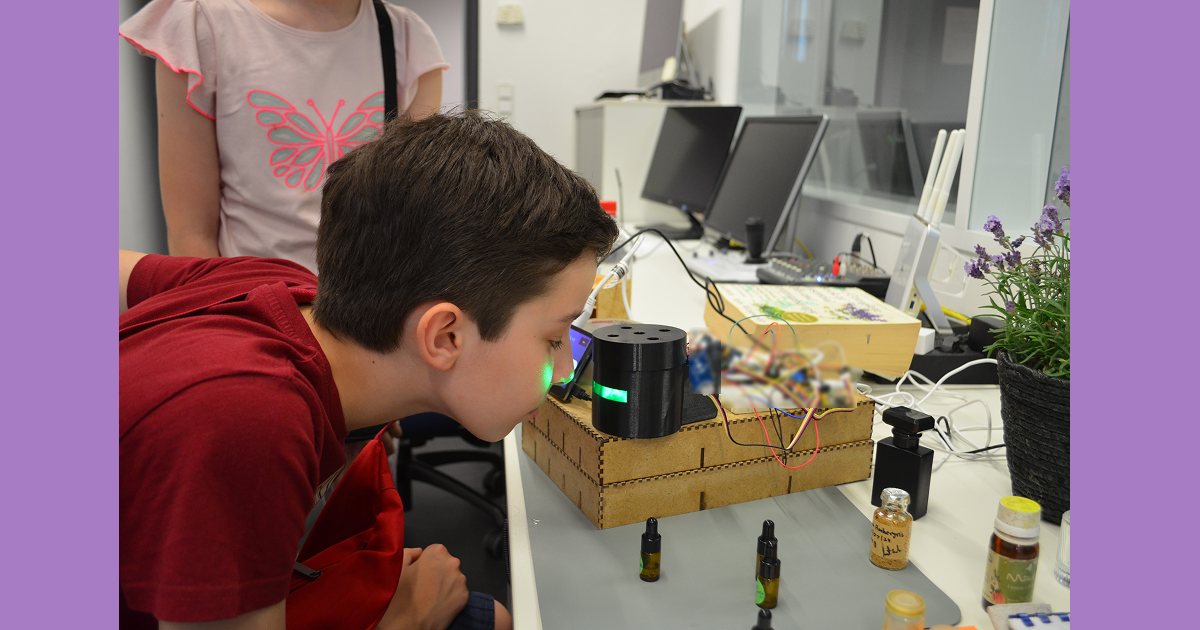 A visitor trying a tabletop Synesthesia olfactory prototype with exposed electronics and scent bottles